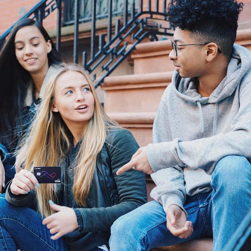 teen holding current bank teen banking debit card with smile