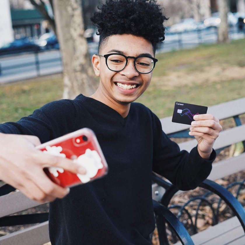 teen holding current bank teen banking debit card with smile